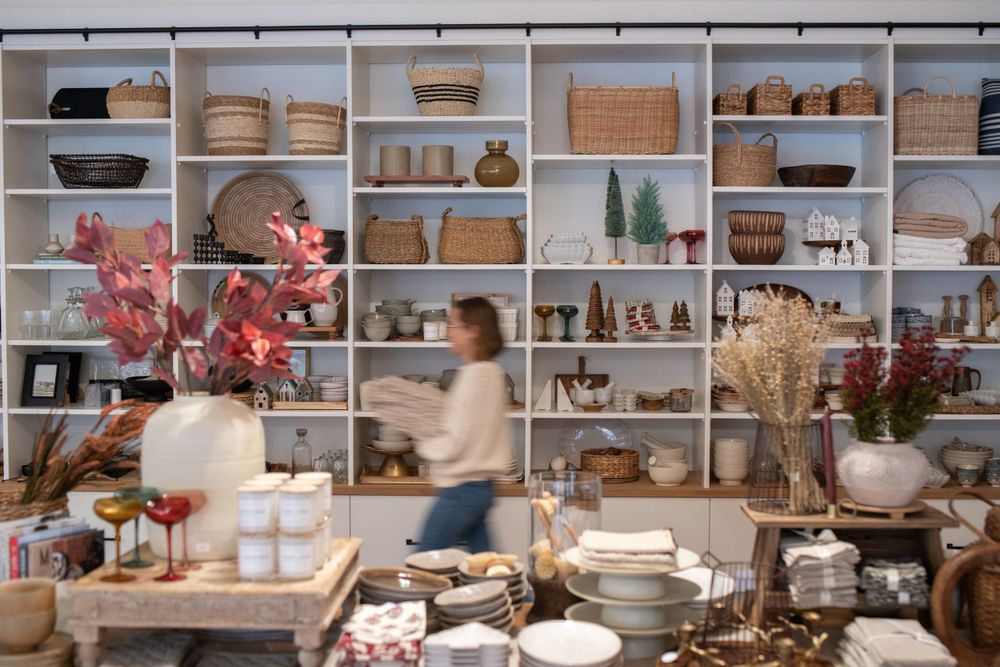 Brand photo of clean and organized retail shelves that display baskets, ceramics, linens, and home decor items in a bright shop setting.