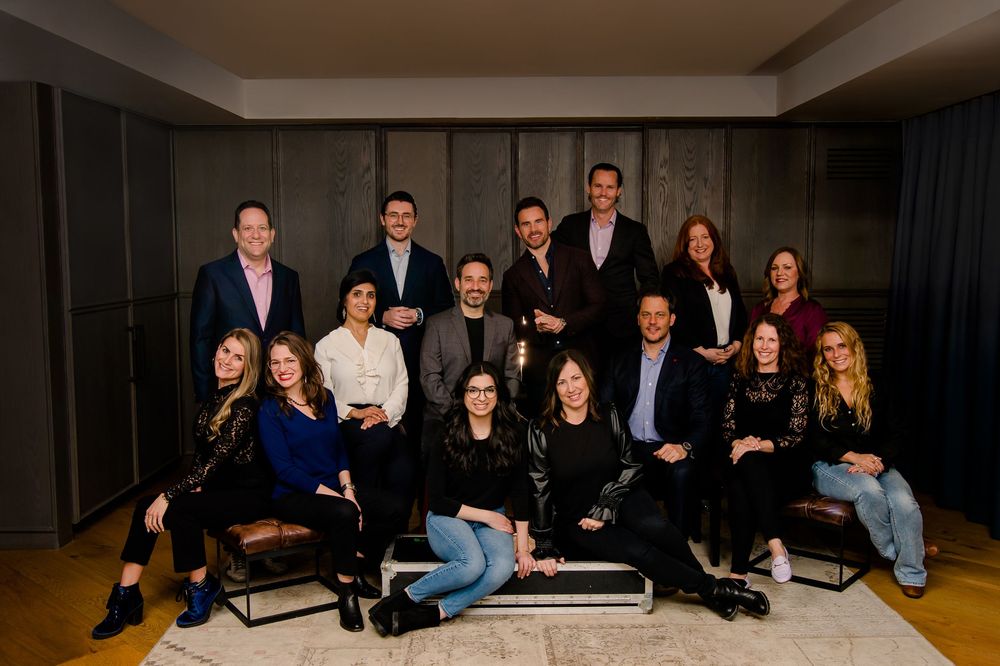 A group of company team members sitting in a casual formation for a corporate photo shoot.
