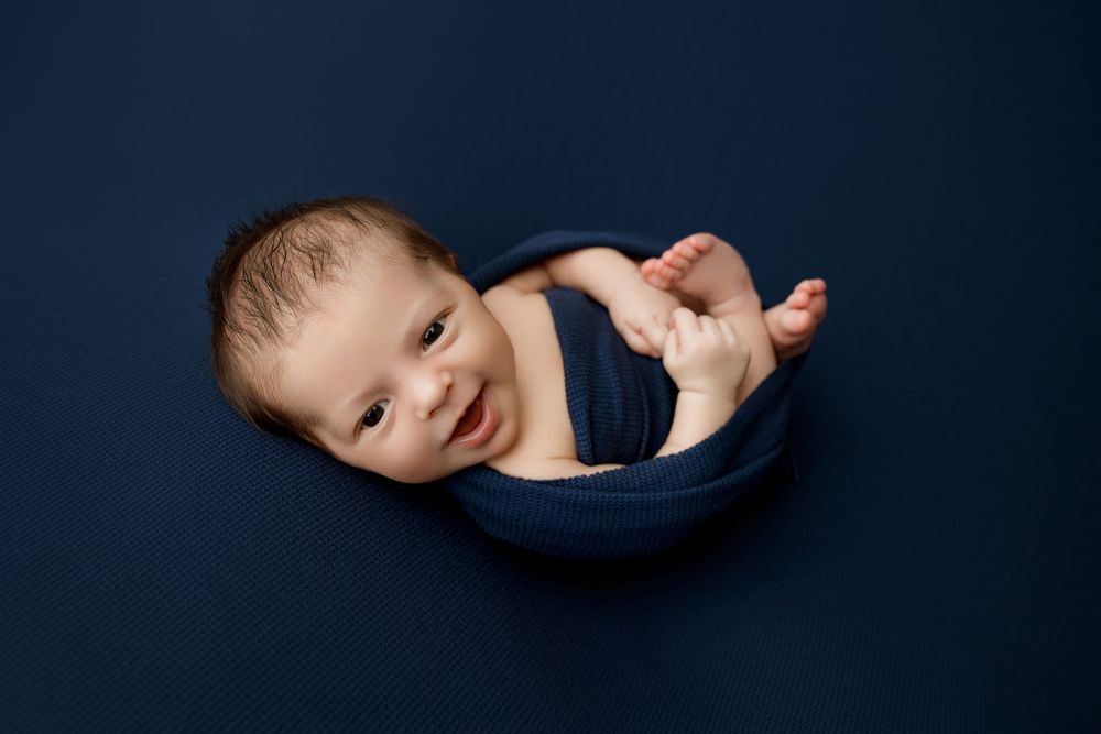 Smiling Newborn in navy half wrapped pose