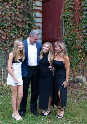 An elegant family portrait against a red brick wall covered in ivy.