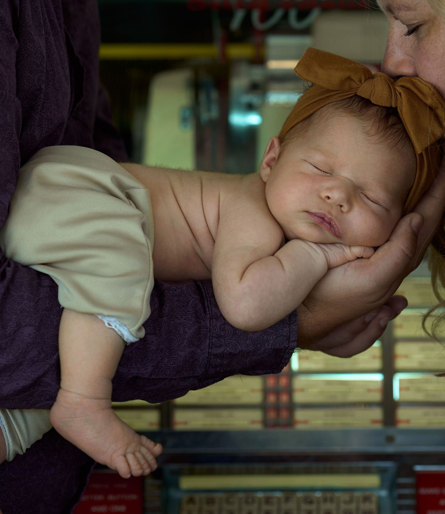Artistic newborn portrait with baby wearing bow headband resting peacefully.