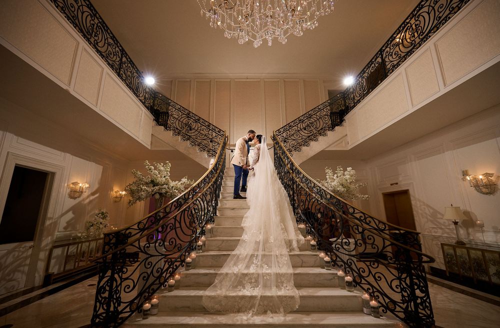 Ornate wrought iron staircase railing with elegant crystal chandelier in a luxury interior hallway.