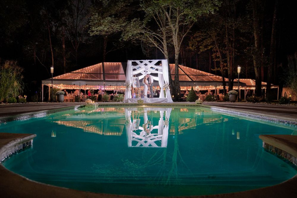 Illuminated outdoor swimming pool at dusk with glowing turquoise water and architectural details around the perimeter.