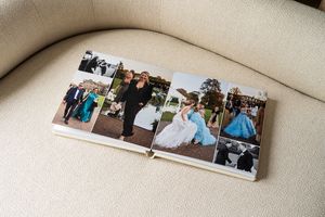 Collection of photo albums laid out on a cream colored couch or sofa displaying wedding memories.