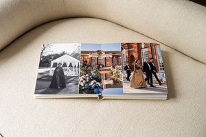 A white leather photo album with multiple wedding photos spread across an open page creating a beautiful layout.