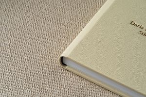 Several close-up images showing different positions and details of a vintage beige book with bound pages and textured cover.