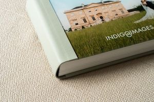 Row of hardcover books in green and white tones aligned on a textured surface with faded lighting.