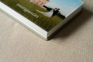 Multiple white wedding photo albums arranged on beige carpet surface.