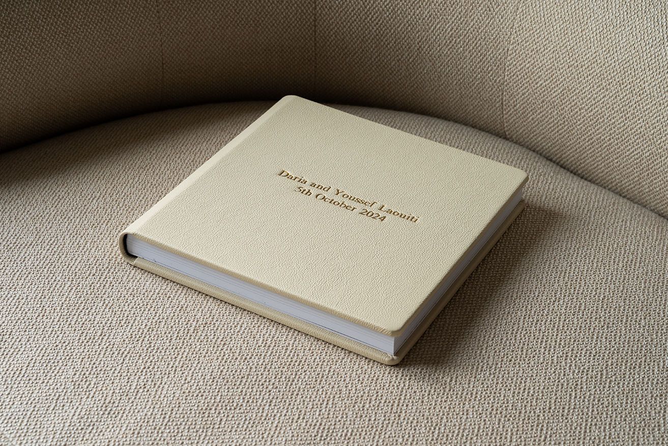 Row of elegant white wedding albums lying flat on neutral colored surface.