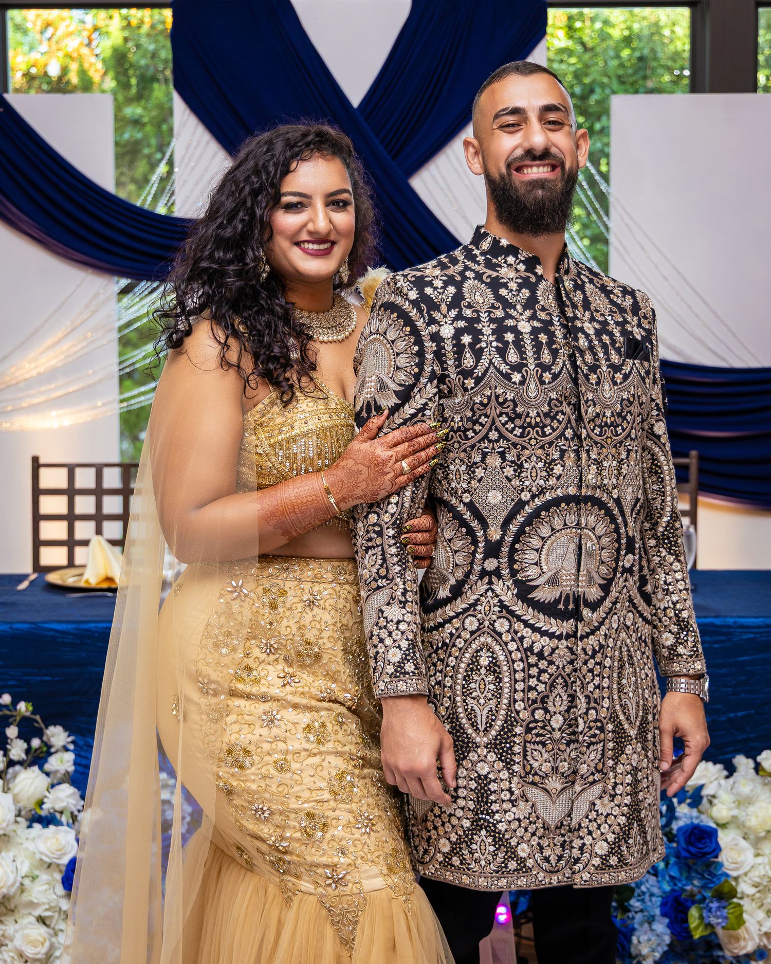 A couple in formal attire share joyful moments at an event with blue and white decor elements.