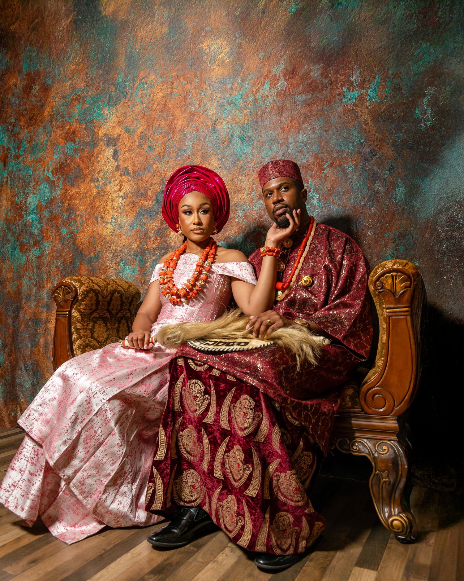 A romantic photoshoot on a textured teal backdrop with traditional Nigerian formal attire and antique furniture.