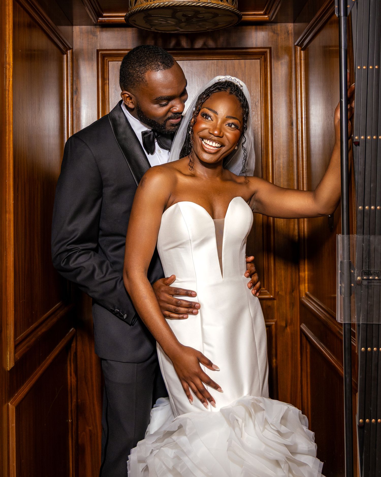 A couple shares an intimate moment in a wood-paneled room during their wedding photoshoot.