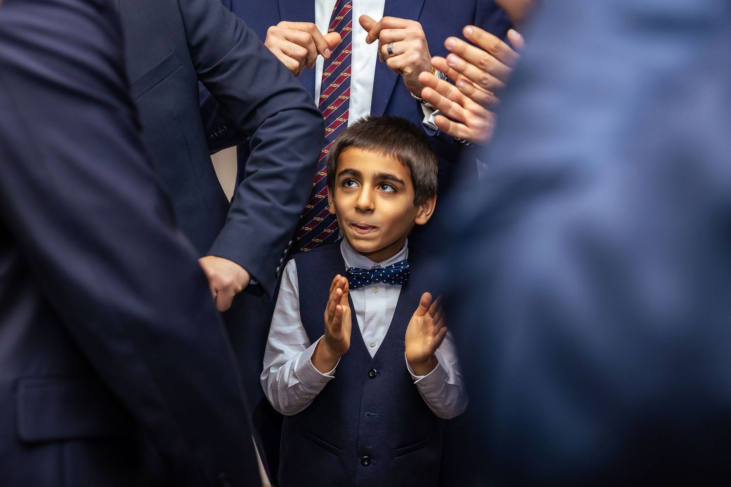 A person in a dark suit and tie gestures while speaking at a podium during a formal event.