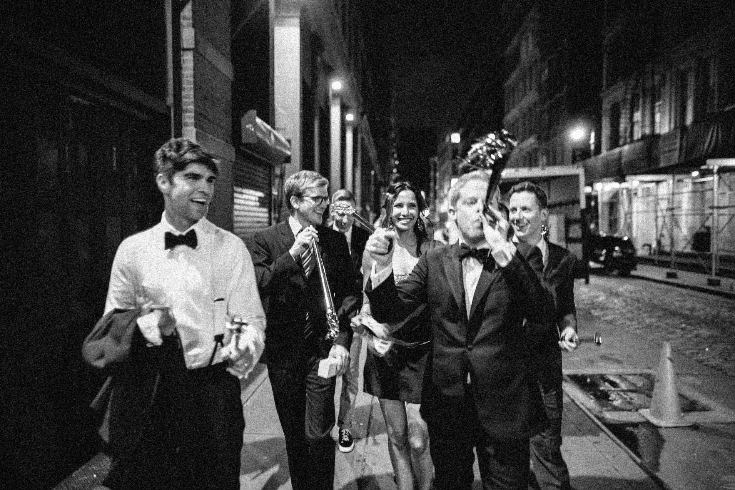 Group walking down a city street at night in formal attire celebrating.