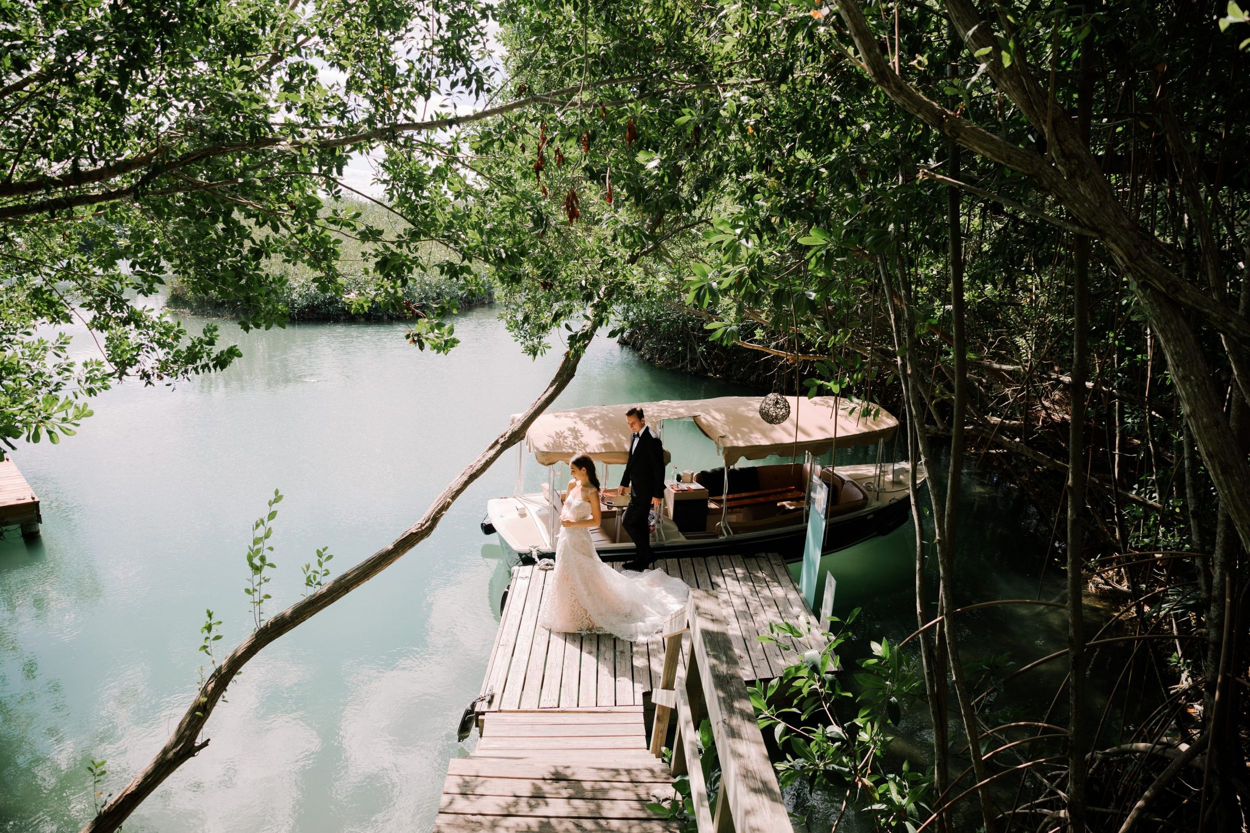 Wooden dock platform extending over tranquil water surrounded by lush green trees and foliage.