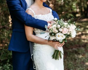 Wedding couple holding elegant white and blush floral bouquet against natural backdrop.Middle TN wedding photographer.