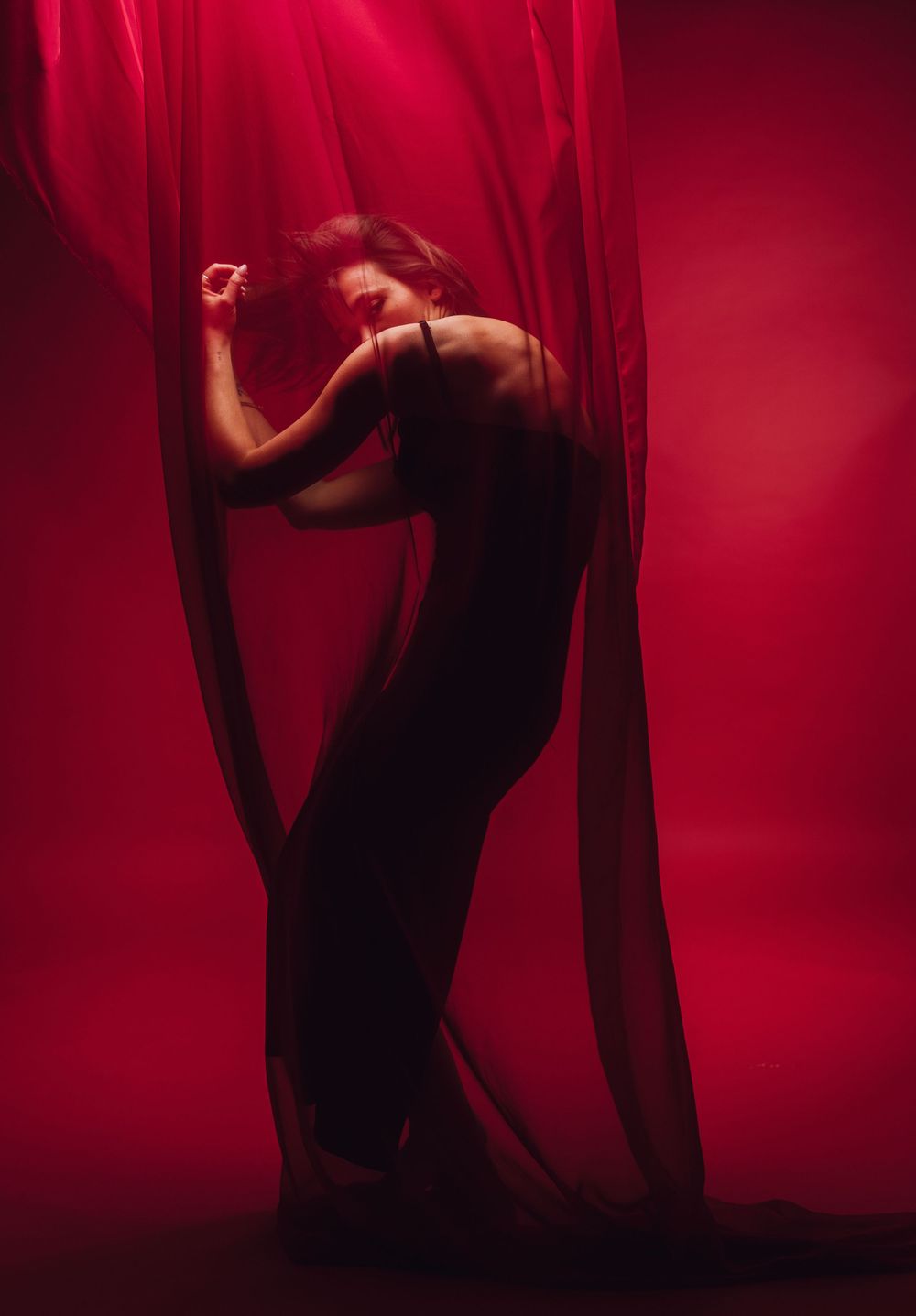 Expressive dance movements captured against a deep red background with flowing fabric.