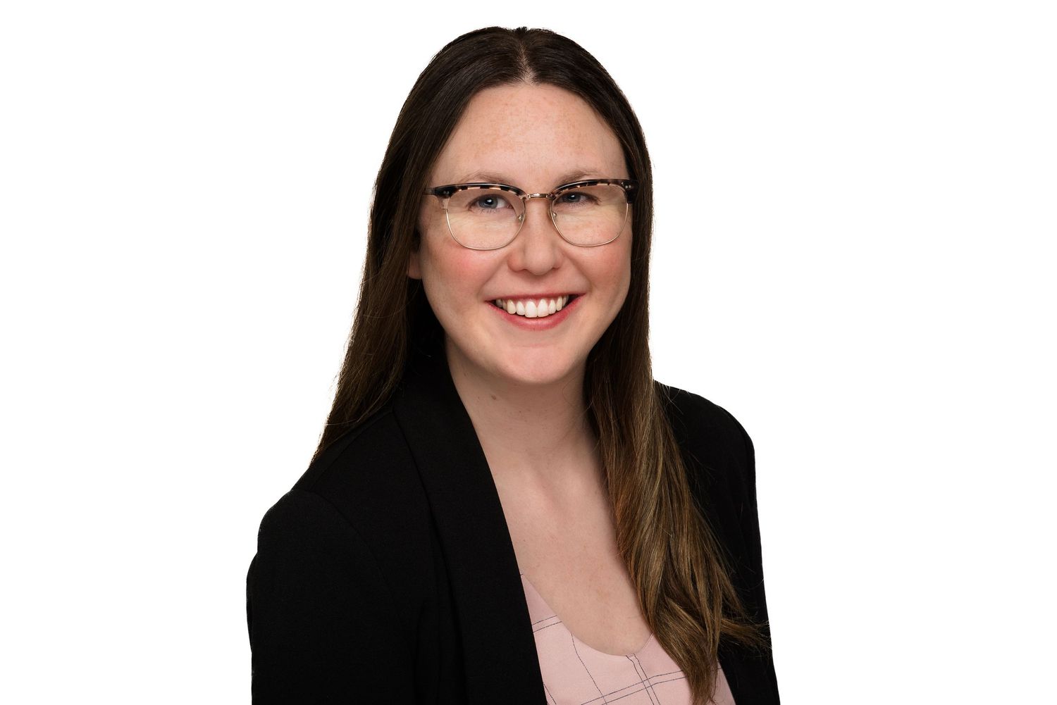 Professional headshot of someone with long dark hair and glasses wearing a black blazer against a white background.