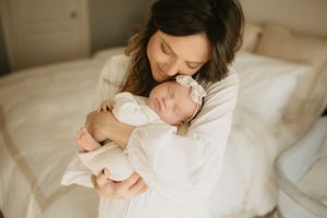 Family shares intimate moments together on white bedding in natural light setting.