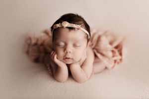 Artistic newborn photography with soft pink tones and delicate wrapping.