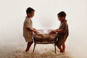 Two young children playing with a wooden toy in a heartwarming vintage-style sepia photograph.