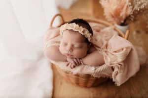 Sleeping newborn wrapped in delicate pink lace with matching headband.