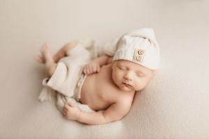 Peaceful newborn baby resting on soft beige fabric.