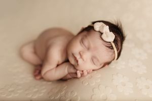 Sleeping newborn on textured cream background with delicate lighting.
