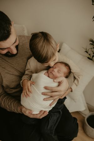 A series of intimate black and white photographs showing tender moments between parent and baby in soft lighting.