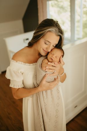 Tender moment in white eyelet dress by sunlit window.