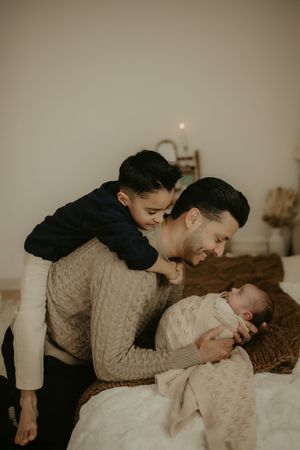 A tender moment captured in warm sepia tones as a parent shares affection with a young child on a bed.