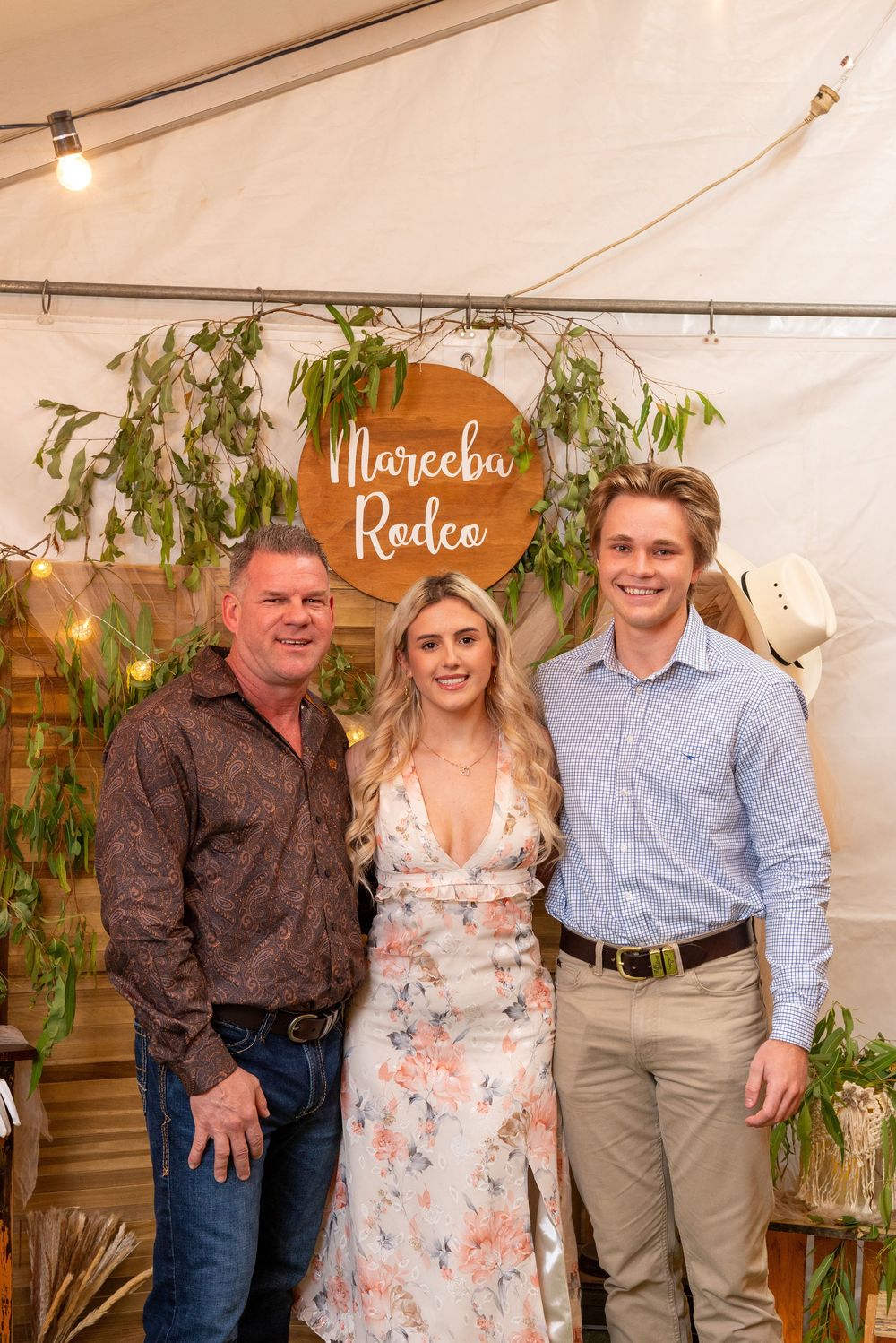 Group photo in a rustic event tent with floral decorations and greenery at a wedding celebration.