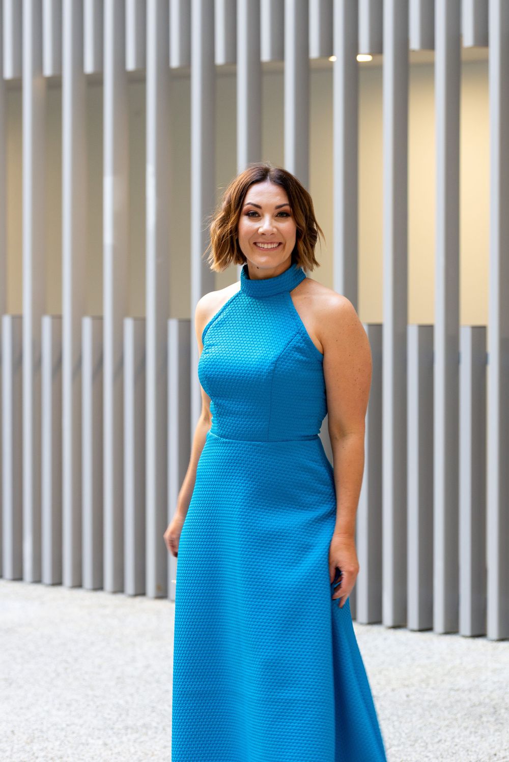 A collection of poses featuring a sleeveless bright blue dress against a modern architectural background.