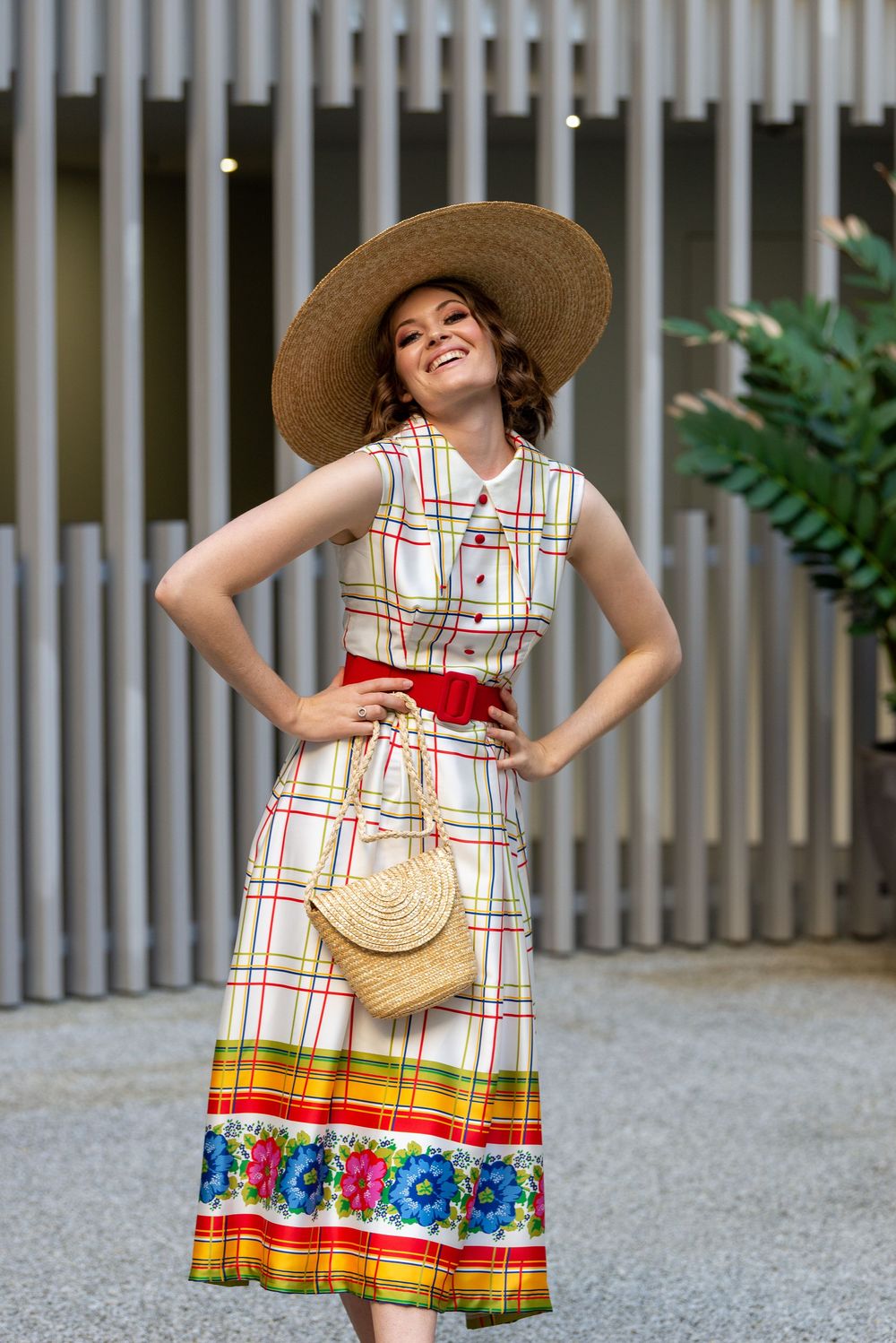 Joyful movement captured in four photos wearing a colorful plaid sundress with hat against gray fence background.