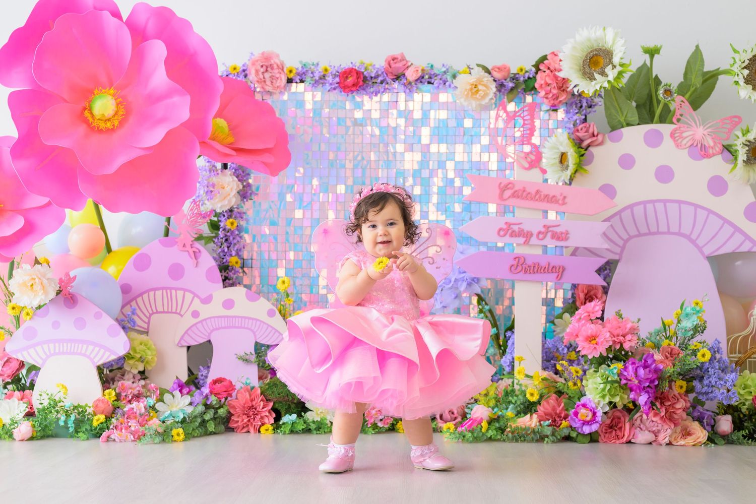 Enchanted fairy garden themed birthday party setup with pink flowers, mushrooms and whimsical decorations.