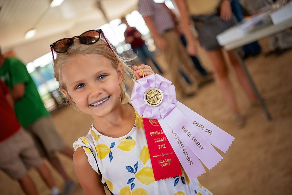 Young participants display award ribbons at a county fair competition.