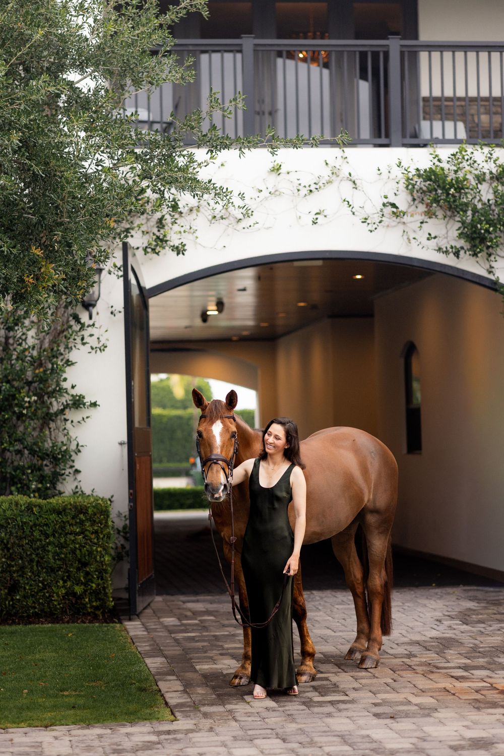 A beautiful chestnut horse stands in an elegant covered courtyard.