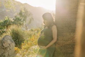 A person stands in a sunlit field of yellow wildflowers with palm trees silhouetted against a glowing sky in Palm Desert