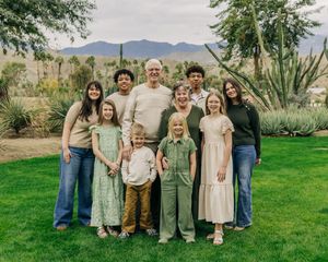 A family group poses together on a green lawn with desert mountains and desert landscaping in the background.