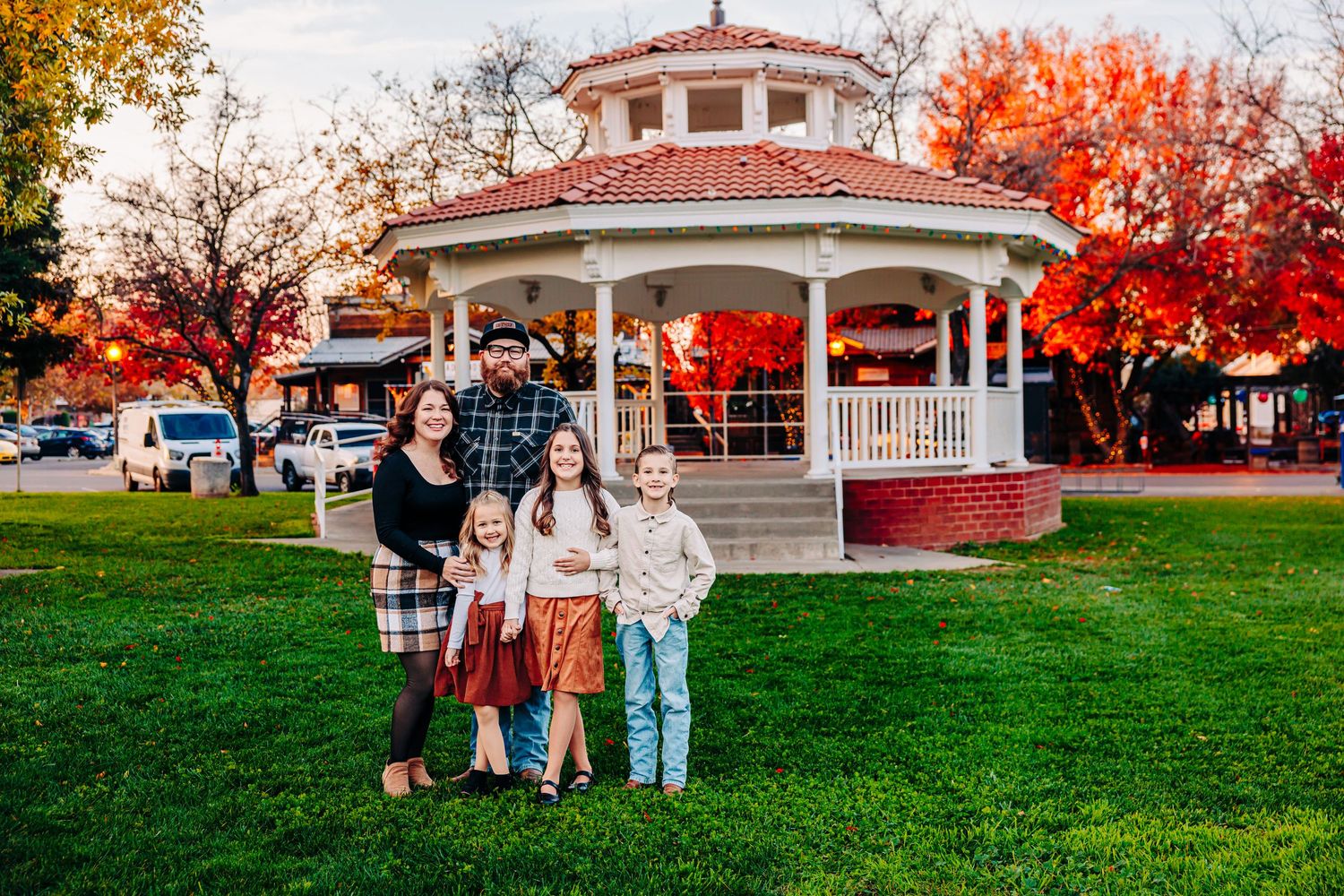 A collection of outdoor autumn photos with vibrant red and orange foliage surrounding a white gazebo in a park setting.