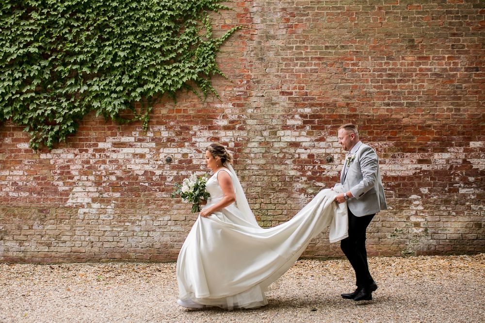 Wedding photography session against an ivy-covered brick wall in a garden setting.