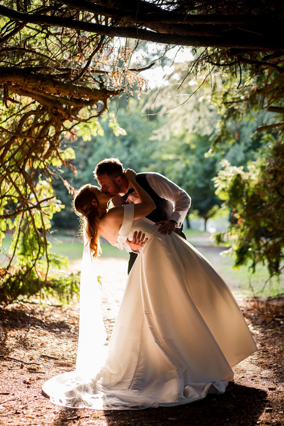 Romantic silhouette shots of couple in wedding attire against sunlit natural backdrop.