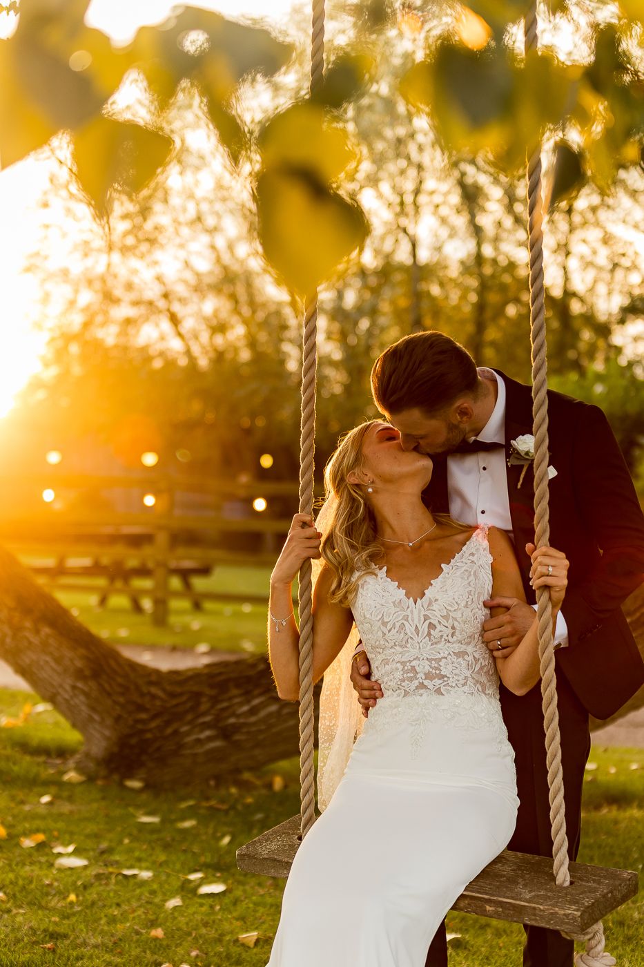 Romantic sunset scene with a wooden swing in a garden setting.