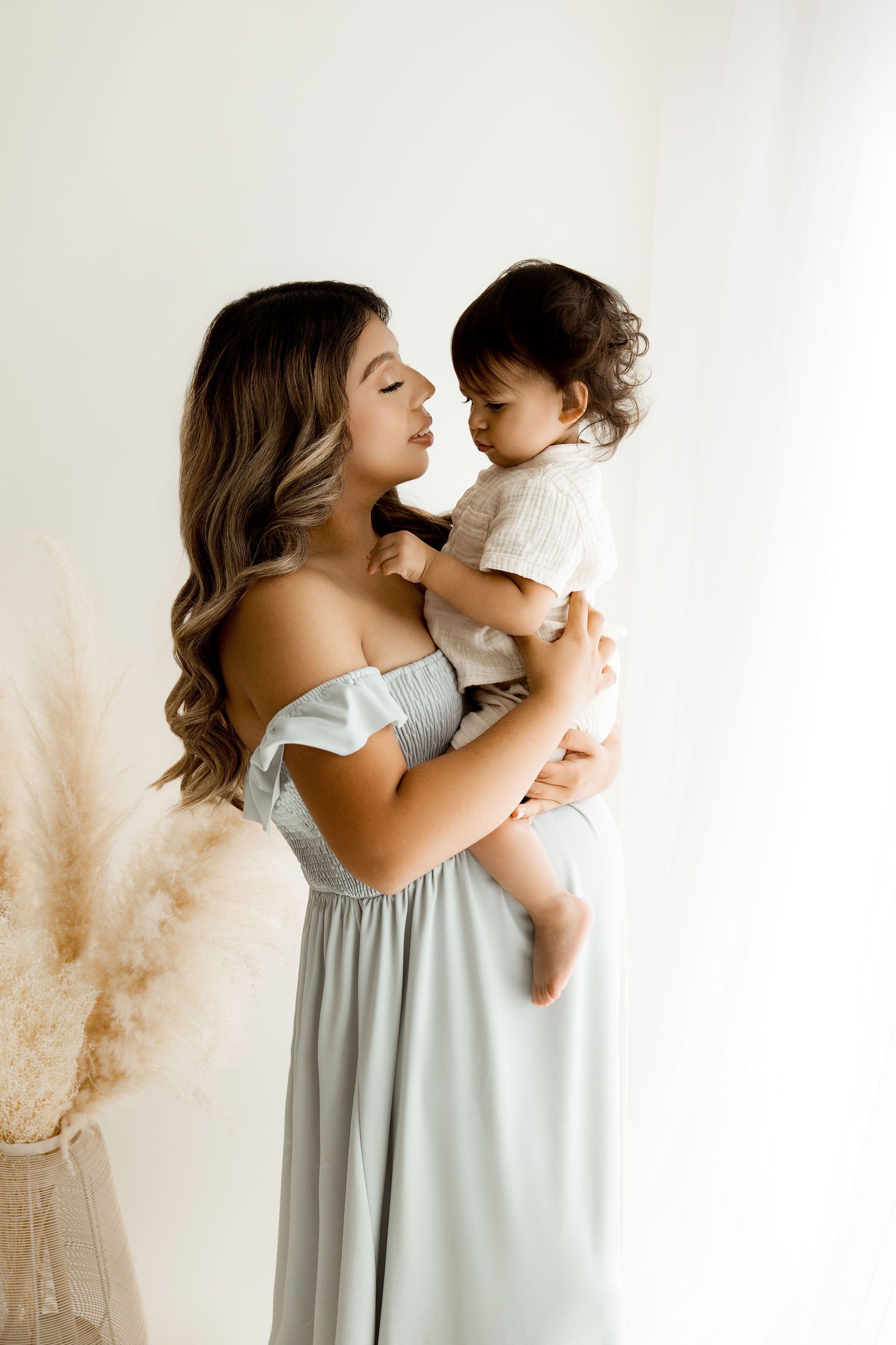 Expectant mom holding her toddler and looking at him
