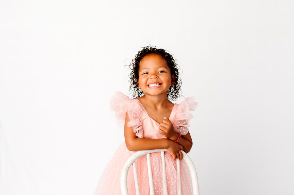Young African American girl with the sweetest smile set against a white indoor photography studio in broken arrow oklahoma
