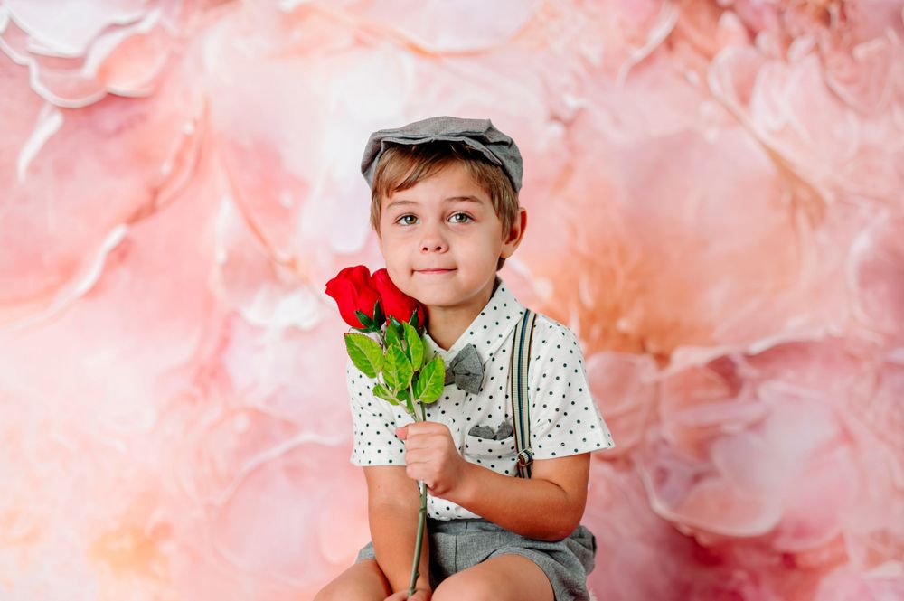 newsies style young boy with roses against pink floral backdrop at indoor photography studio in broken arrow