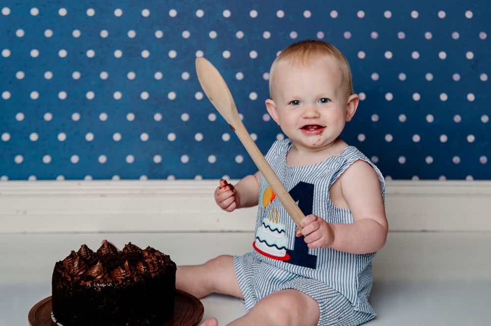 broken arrow tulsa indoor photography studio milestone cake smash 1st bday session with young boy. background is blue with white polka dots