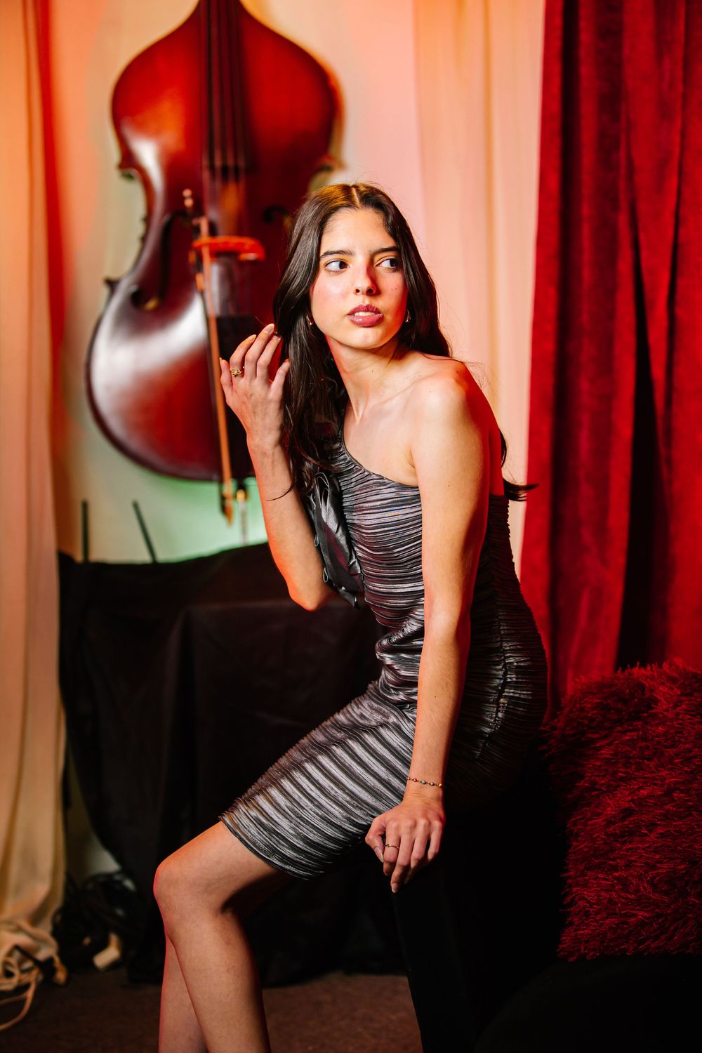 A series of artistic portraits in a moody red-lit studio setting with violin decor and striped dress.