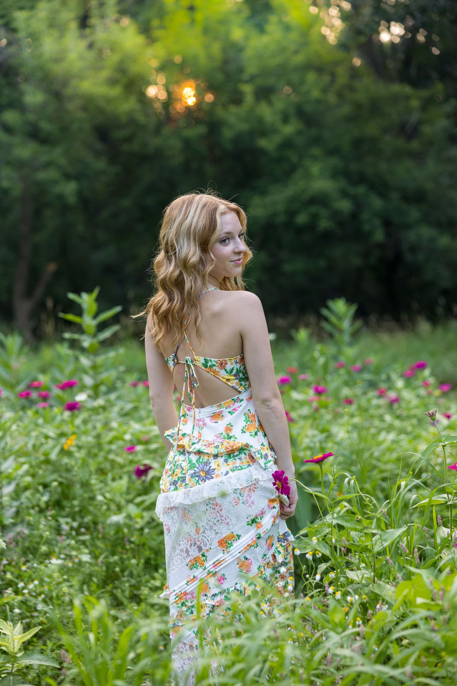 Portrait of woman with blonde wavy hair smiling in garden setting.