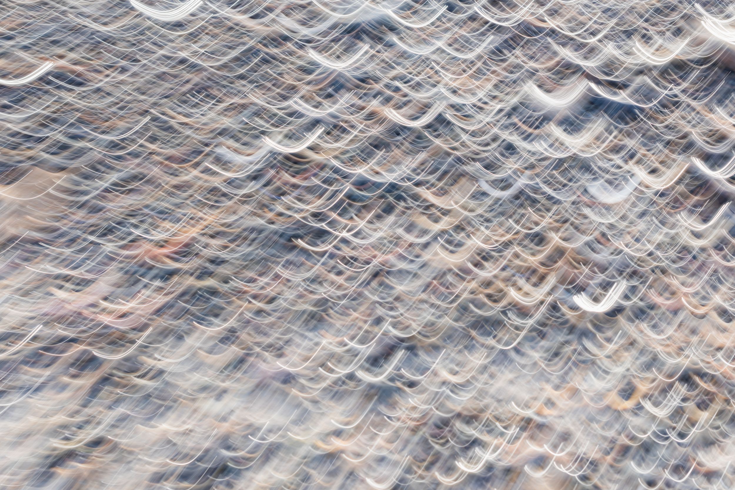 Abstract texture of shallow ocean water washing over sandy beach shore.